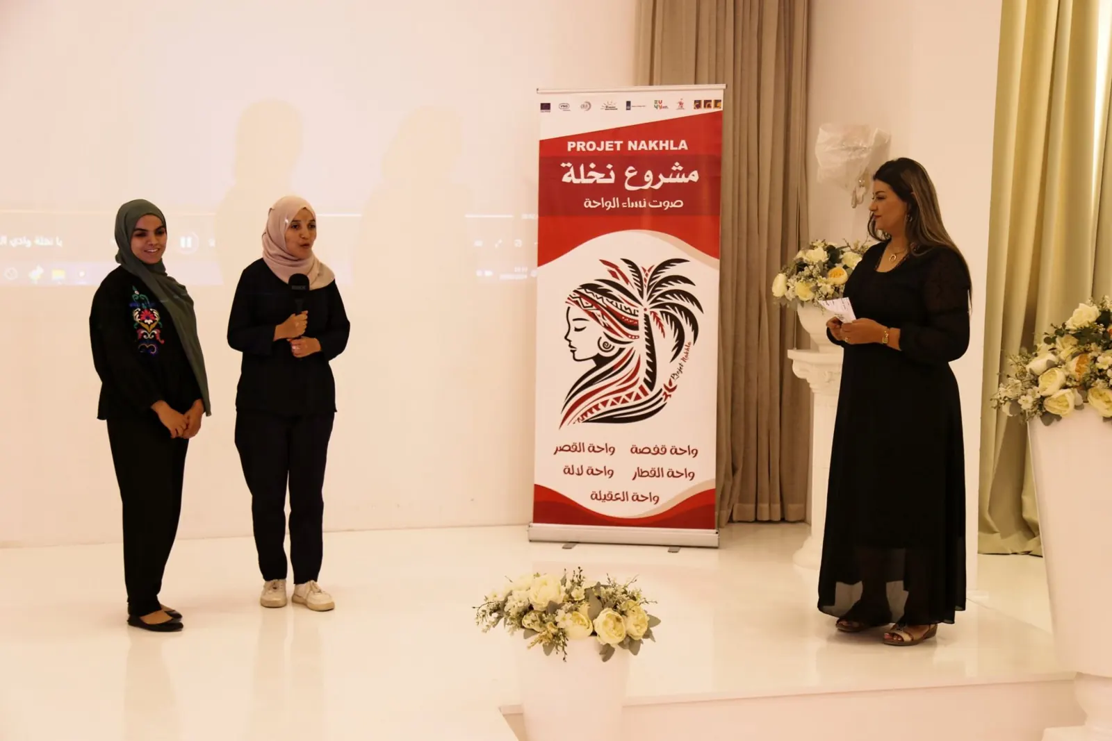 Speaking on stage in front of the Nakhla project banner